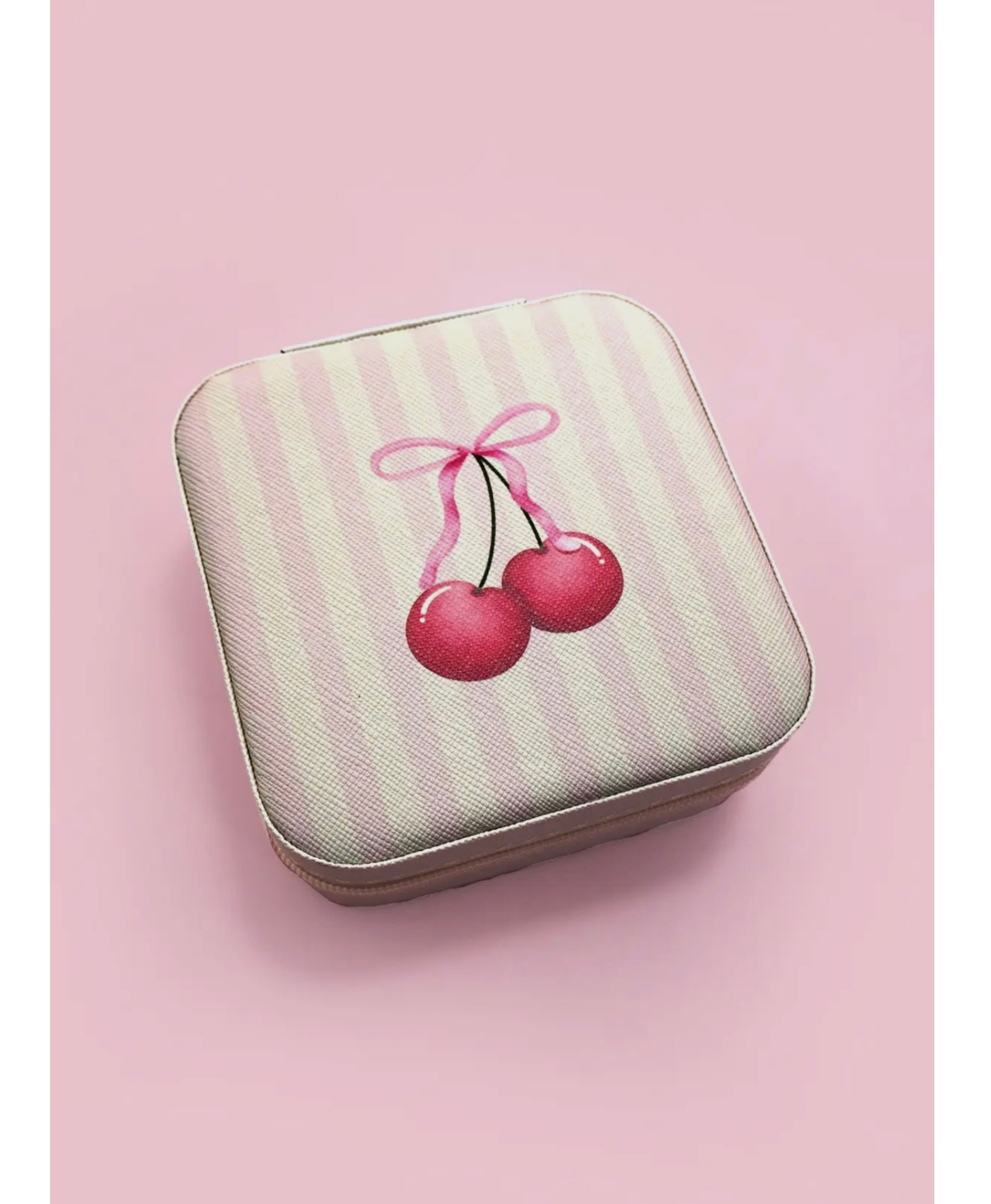Travel jewelry box with pink and white stripes with a cherry and bow on a pink background