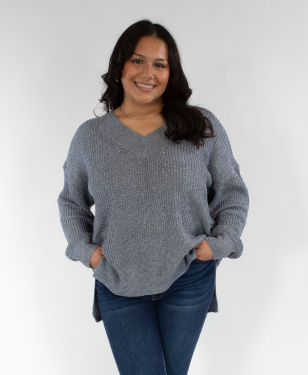 Woman wearing a blue sweater and blue jeans against a white background