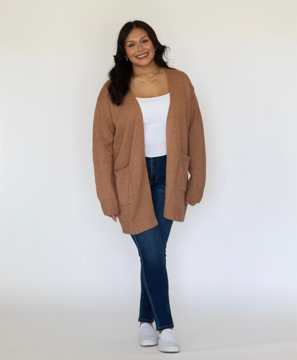 Women wearing a brown color cardigan with a white tank top and jeans on a white background