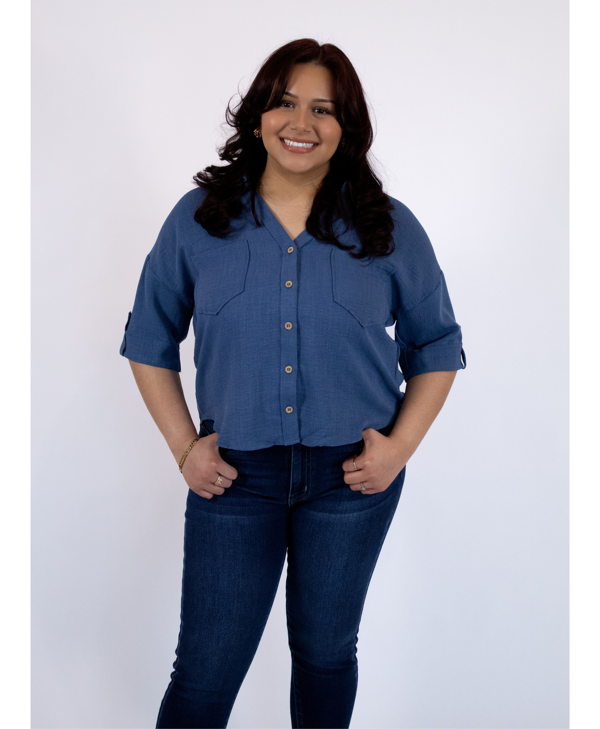 Women wearing a blue button up top with pockets and jeans on a white background