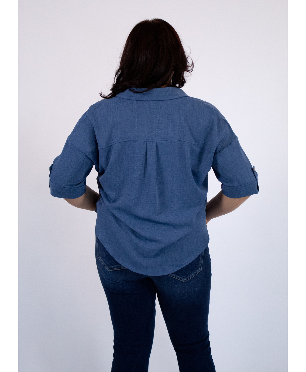 Back of women wearing a blue blouse with jeans on a white background