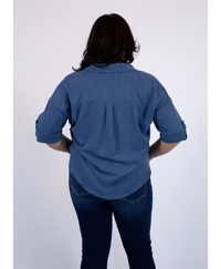 Back of women wearing a blue blouse with jeans on a white background