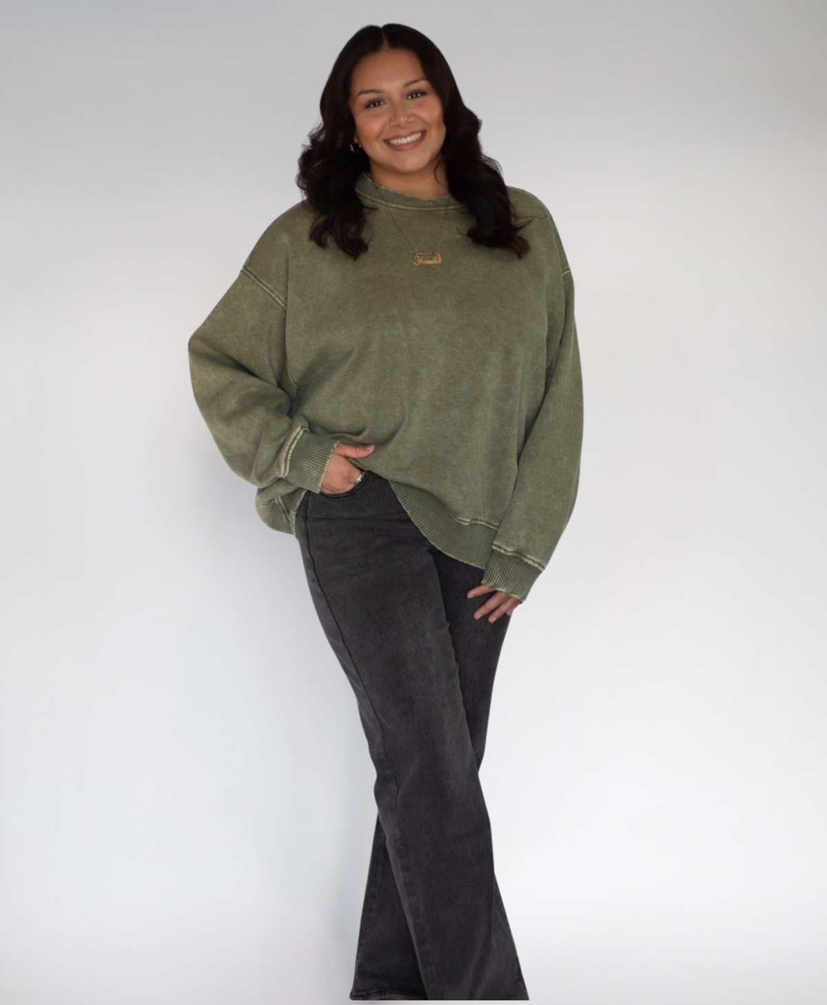 Person wearing a green sweatshirt with black jeans on a white background