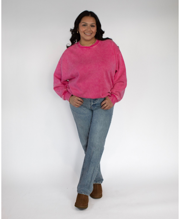 Person wearing a pink sweatshirt and blue jeans on a white background
