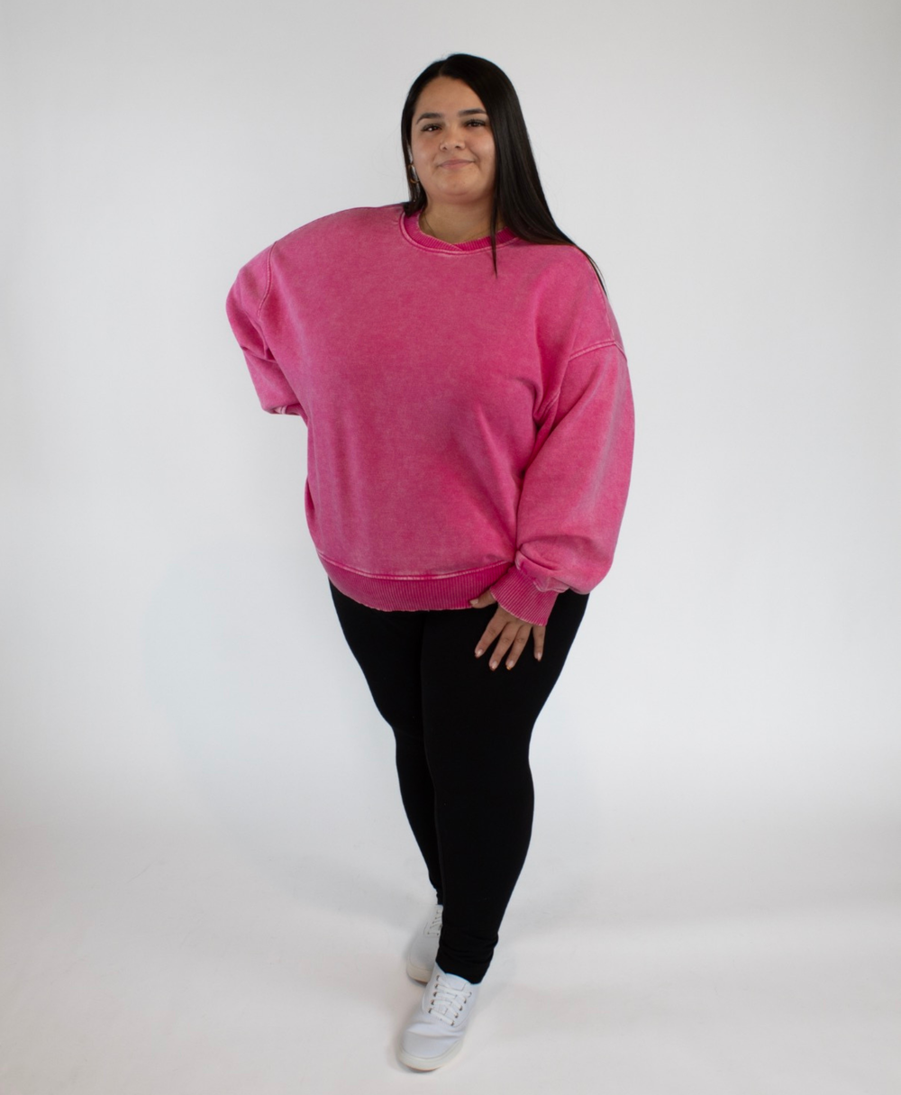 Person wearing a pink sweatshirt and black leggings on a white background