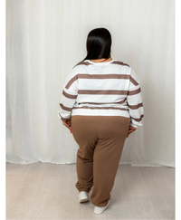 Back of woman wearing a white and brown top with brown joggers