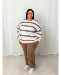 Woman wearing a white and brown top with brown joggers