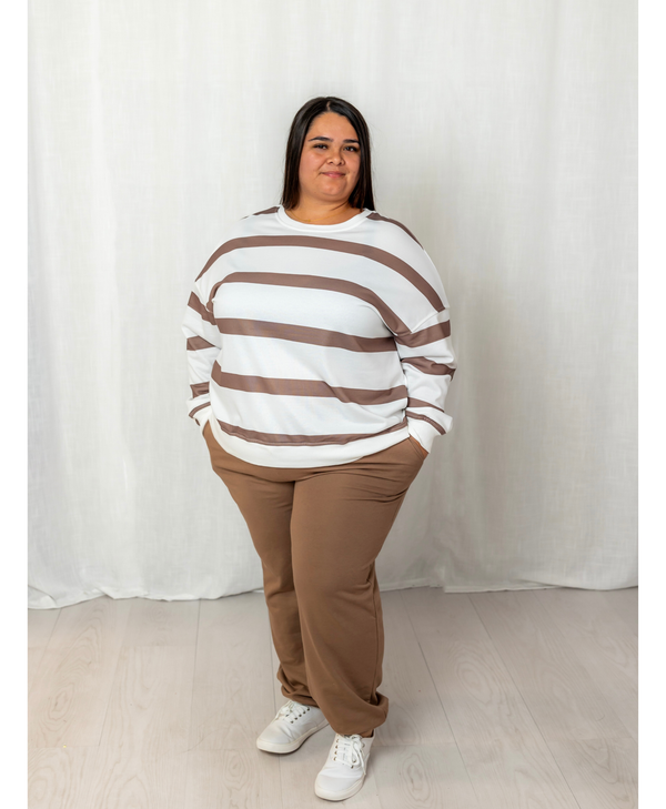 Woman wearing a white and brown top with brown joggers