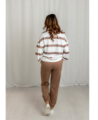 Back of woman wearing white and brown top with brown joggers