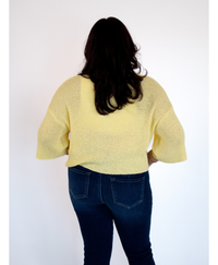 Back of women wearing a yellow top with. jeans on a white background