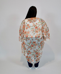Person wearing a floral kimono with jeans on a plain background