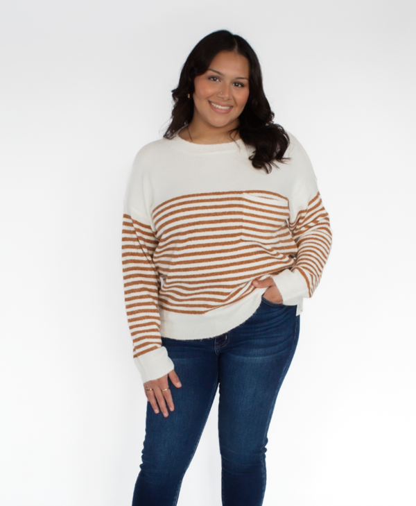 Woman wearing a brown colored striped sweater and jeans on a white background