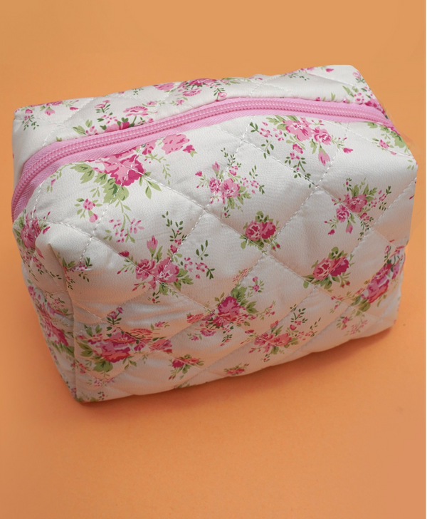 Floral-patterned quilted pouch with a pink zipper on an orange background