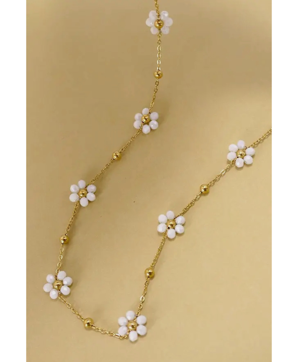 Gold necklace with white flower charms on a yellow background