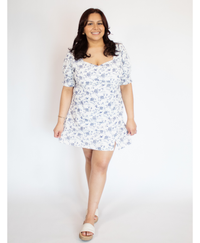 Woman wearing a white with blue floral dress on a white background