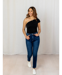 Women wearing a black one shoulder top with jeans on a white background