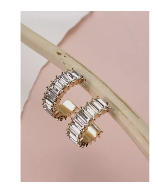 Gold hoop earrings with rhinestones on a pink background