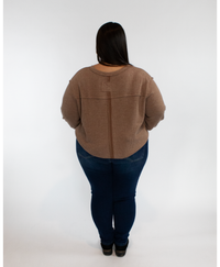 Person wearing a brown long sleeve and dark blue jeans on a white background