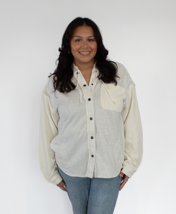 Woman wearing a light gray and cream button-up shacket with a cream pocket with a white background
