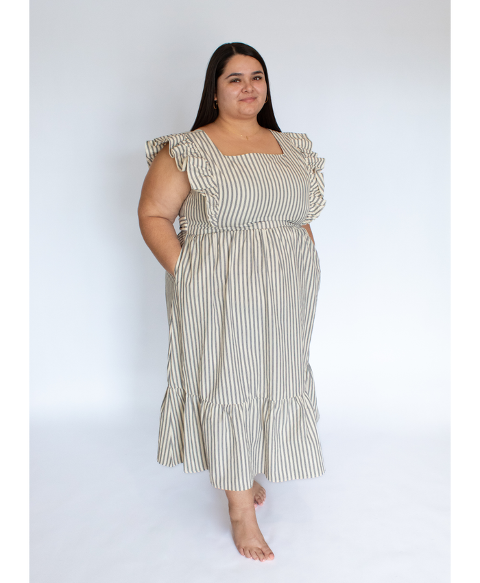 Woman wearing a striped full length cream colored dress with ruffle-trimmed short sleeves  against a white background