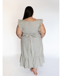 Back of woman wearing a striped full length cream colored dress with ruffle-trimmed short sleeves  against a white background