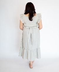 Back of woman wearing a striped full length cream colored dress with ruffle-trimmed short sleeves  against a white background