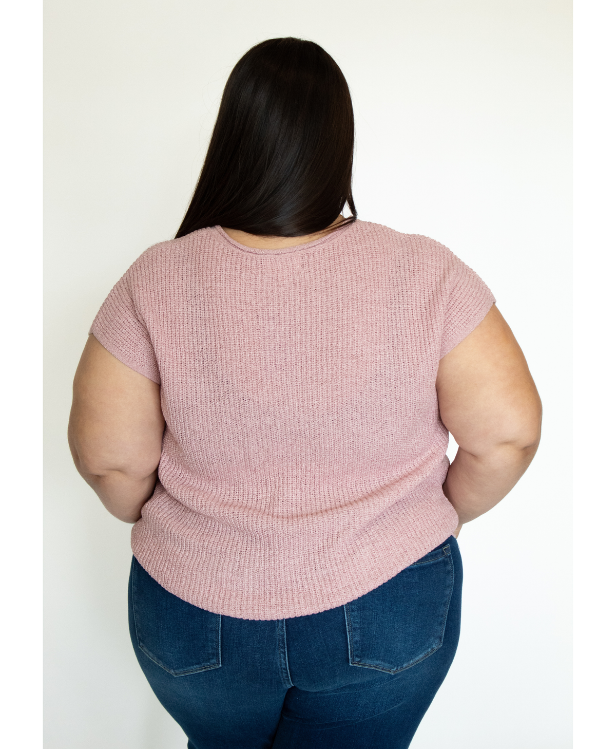 Women wearing a pink short-sleeve top and blue jeans against a white background