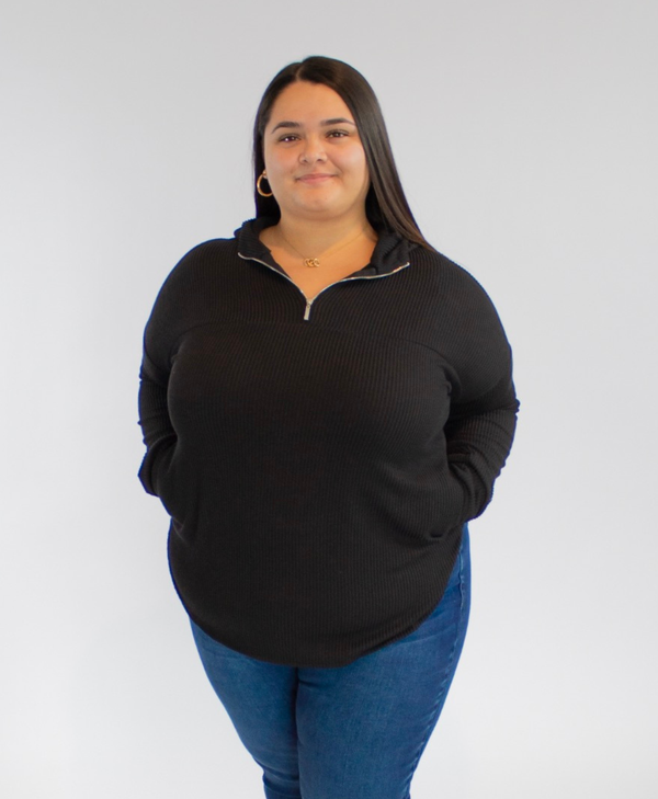 Person wearing a black pullover and blue jeans against a white background