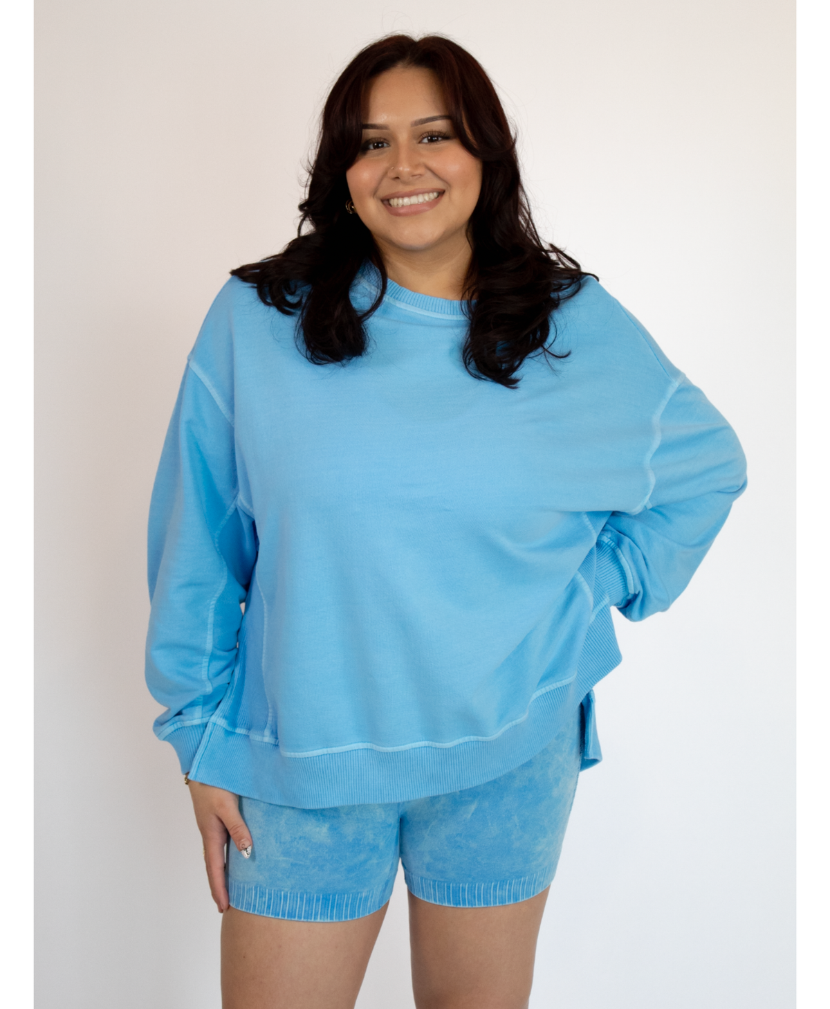 Woman wearing a light blue sweatshirt and shorts set on a white background