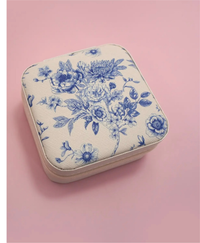 Travel jewelry box with a blue floral print design on a pink background