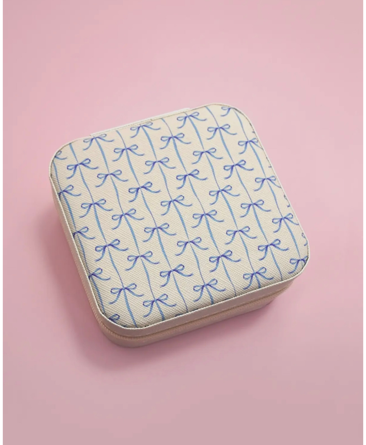 Travel jewelry box with blue bow print on a pink background