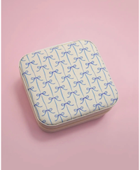 Travel jewelry box with blue bow print on a pink background