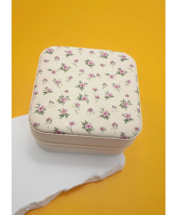 Travel jewelry box with a floral print with pink flowers on a white object and yellow background