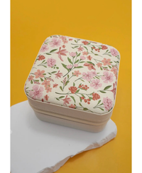 Travel jewelry box with floral print design on it  on a white object on a yellow background