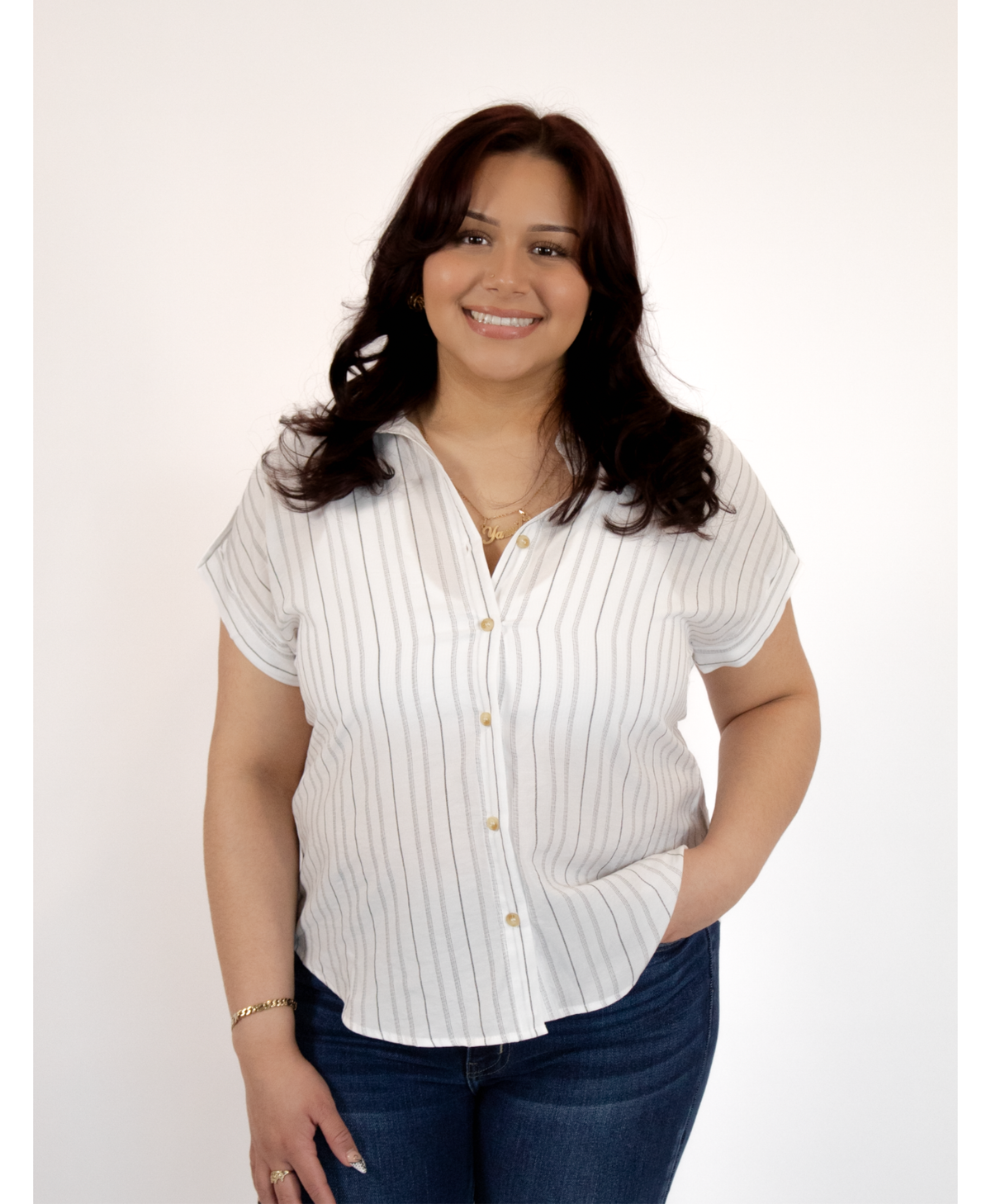Woman wearing a white short-sleeve button-up shirt and blue jeans on a white background
