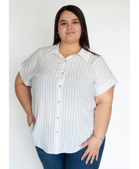 Woman wearing a white striped button up shirt against a plain white background