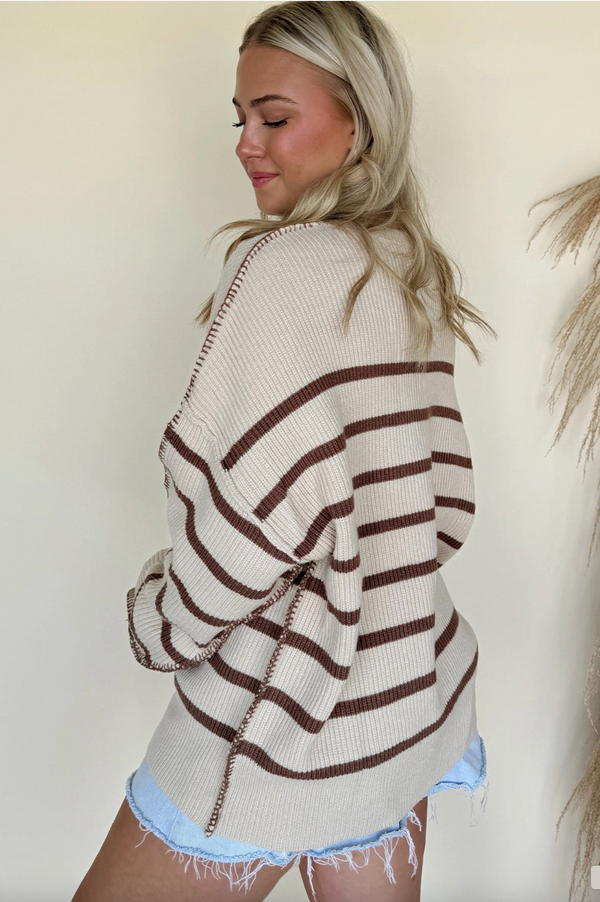 Woman wearing a striped sweater and denim shorts against a plain background